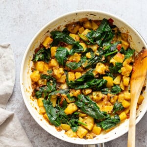 Garlic Potato Spinach Stir fry in a white skillet