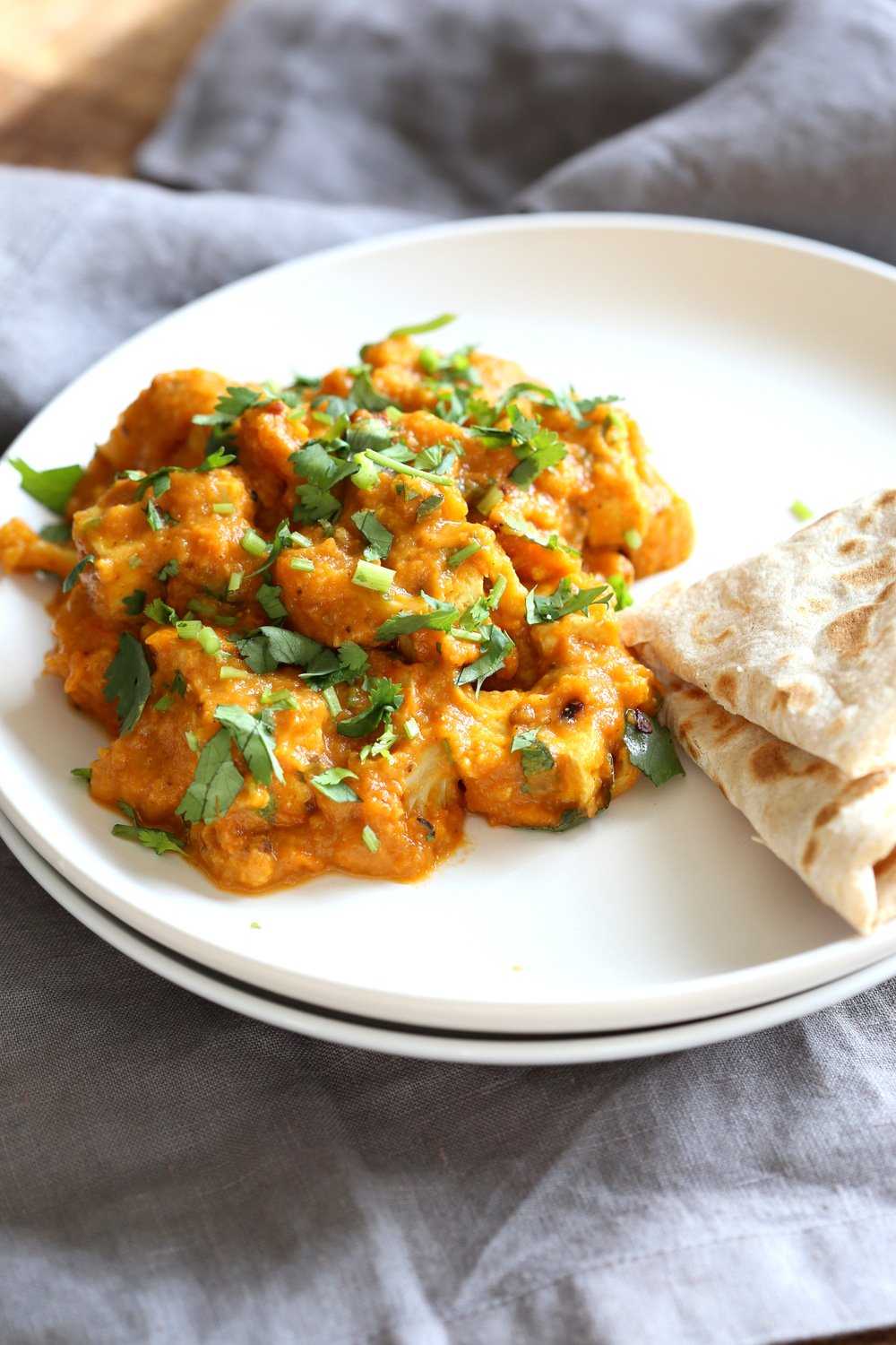 Tofu and Cauliflower in Kolhapuri Sauce in a white plate with flabread
