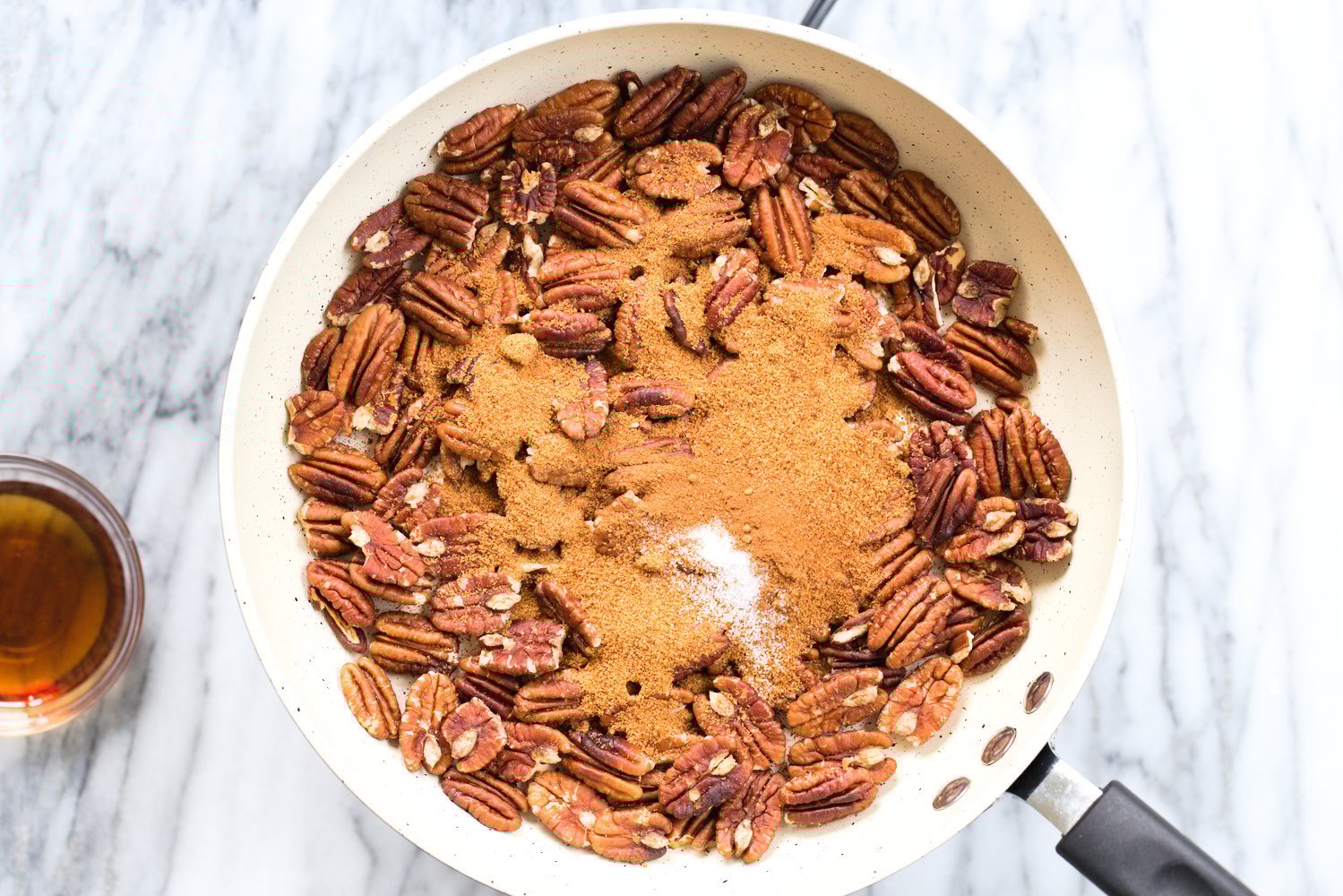 Toasted Pecans, coconut sugar, salt, spice in a white skillet