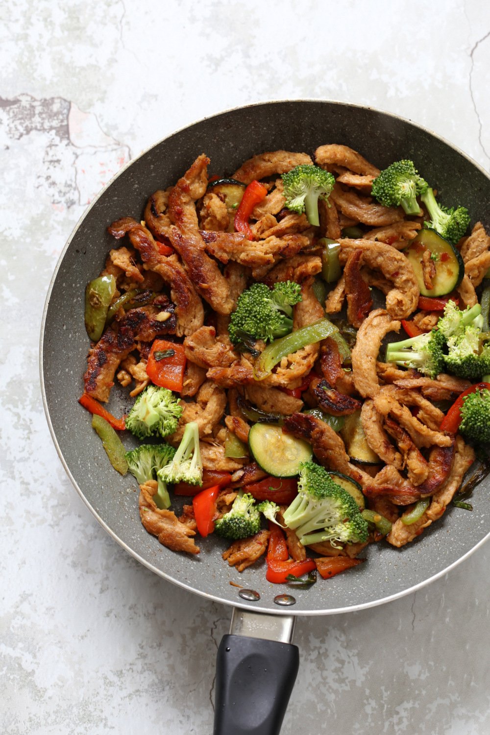Vegegies and soy curls with general tsos sauce in grey skillet