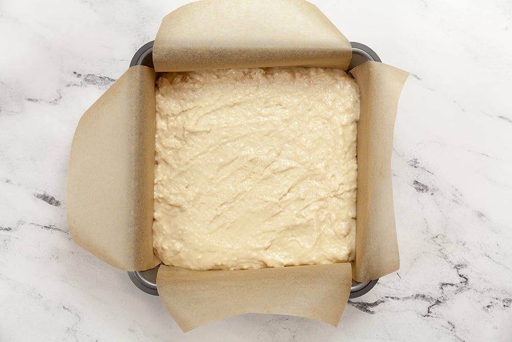 Berry Buckle Batter in a parchment lined baking dish