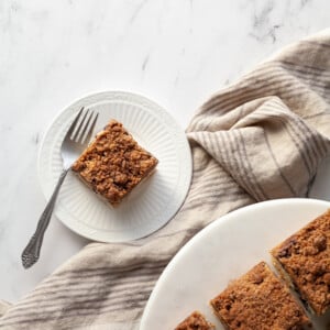 Vegan Blueberry Buckle slice on a white plate with a fork