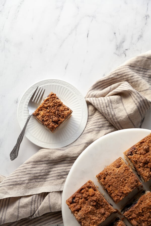 Vegan Blueberry Buckle slice on a white plate with a fork