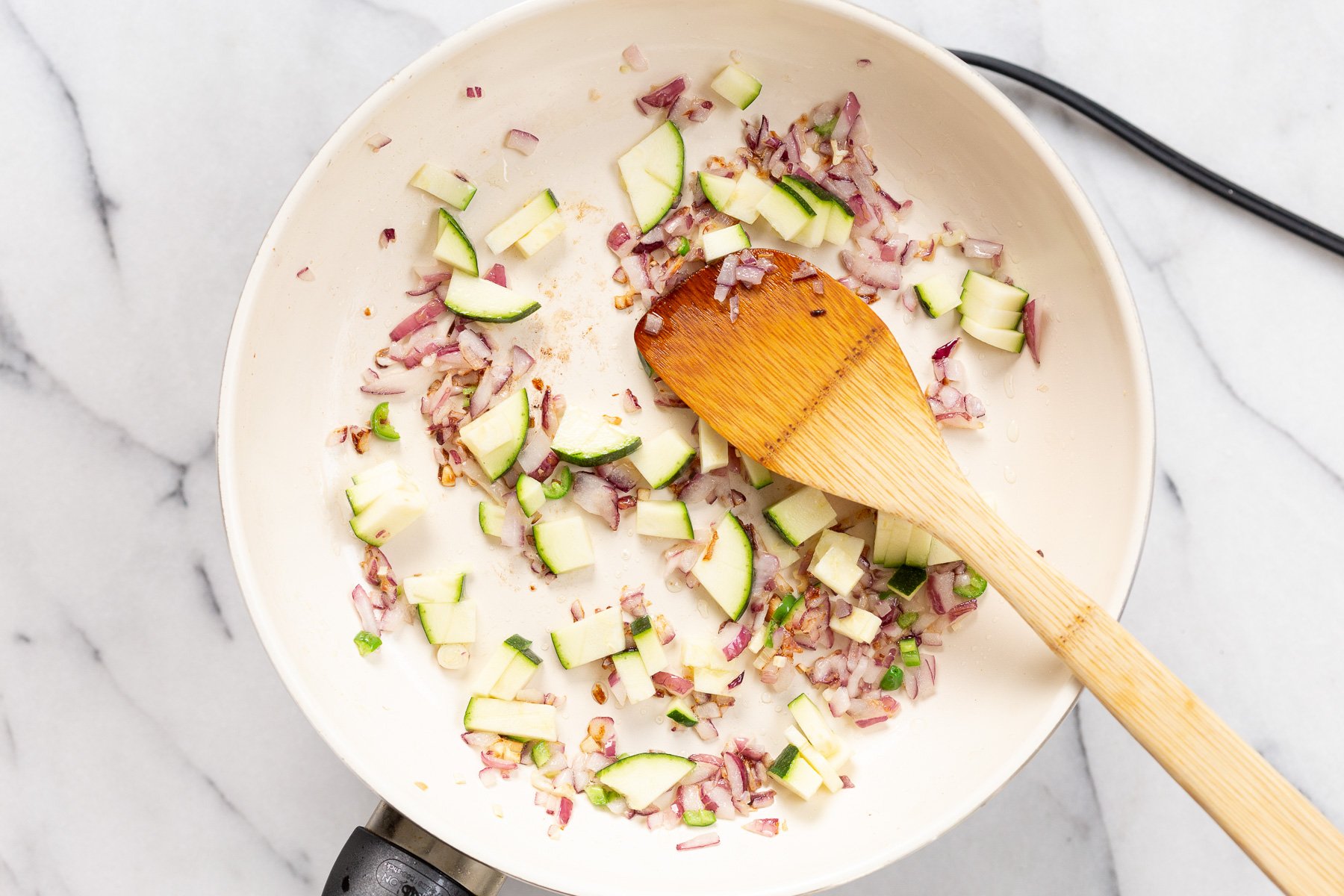 Zucchini and onions in a white skillet for or tofu scramble