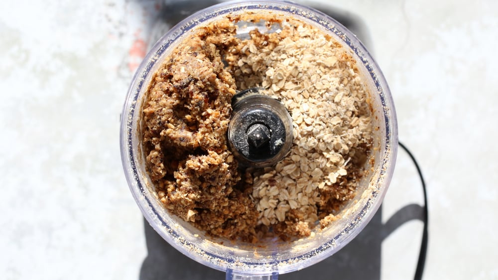 overhead shot of dates and rolled oats in a food processor ready to be combined to make vegan granola bars