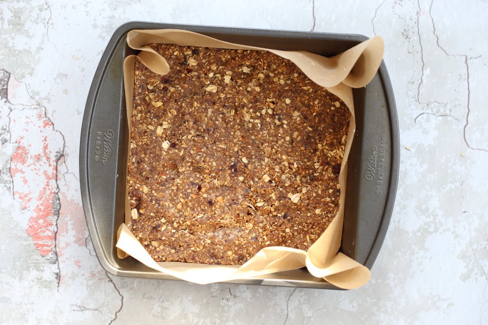 granola batter pressed into a square baking pan