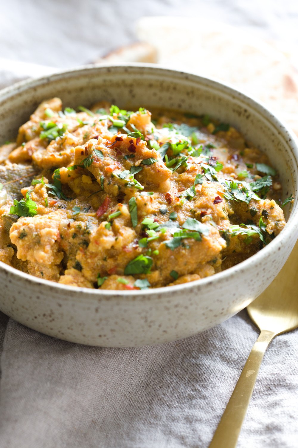 vegan curry recipe  side view of a bowl of creamy vegan methi chicken curry topped with chopped cilantro
