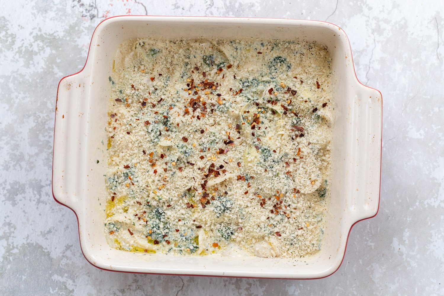 spinach artichoke pasta bake topped with breadcrumb topping ready to go in the oven