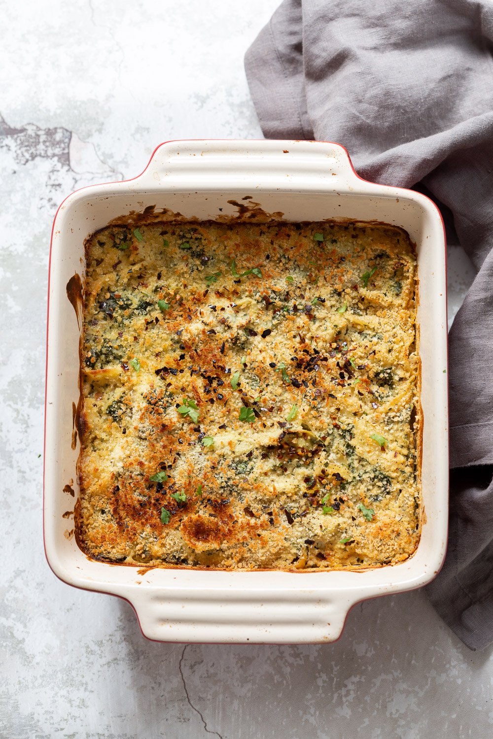 spinach pasta recipe  overhead shot of a vegan spinach and artichoke pasta bake with breadcrumb topping