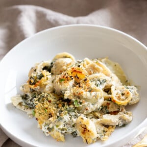 a serving of vegan spinach and artichoke pasta bake on a white plate