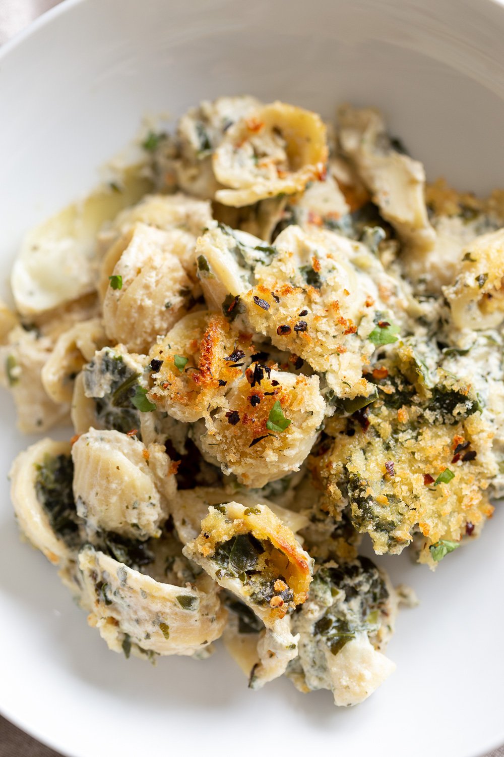 spinach pasta recipe overhead shot of a plate of vegan spinach and artichoke pasta bake with breadcrumb topping