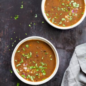overhead shot of two bowls of vegan black bean soup against black background