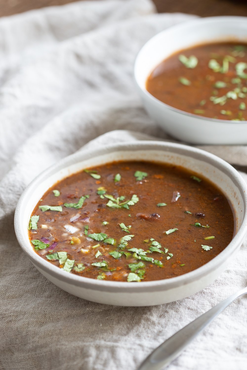 vegan black bean soup  side view of a bowl of vegan Instant Pot black bean soup on a white cloth napkin