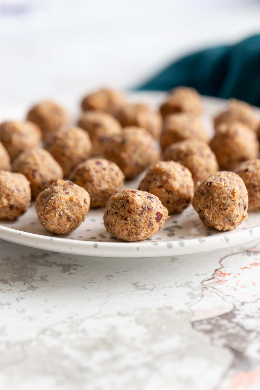 coconut balls  side view of a plate with vegan coconut caramel date energy balls