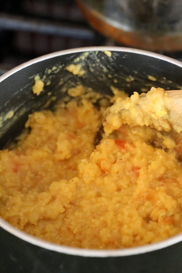 cooked red lentils being mashed in a saucepan to make red lentil hummus