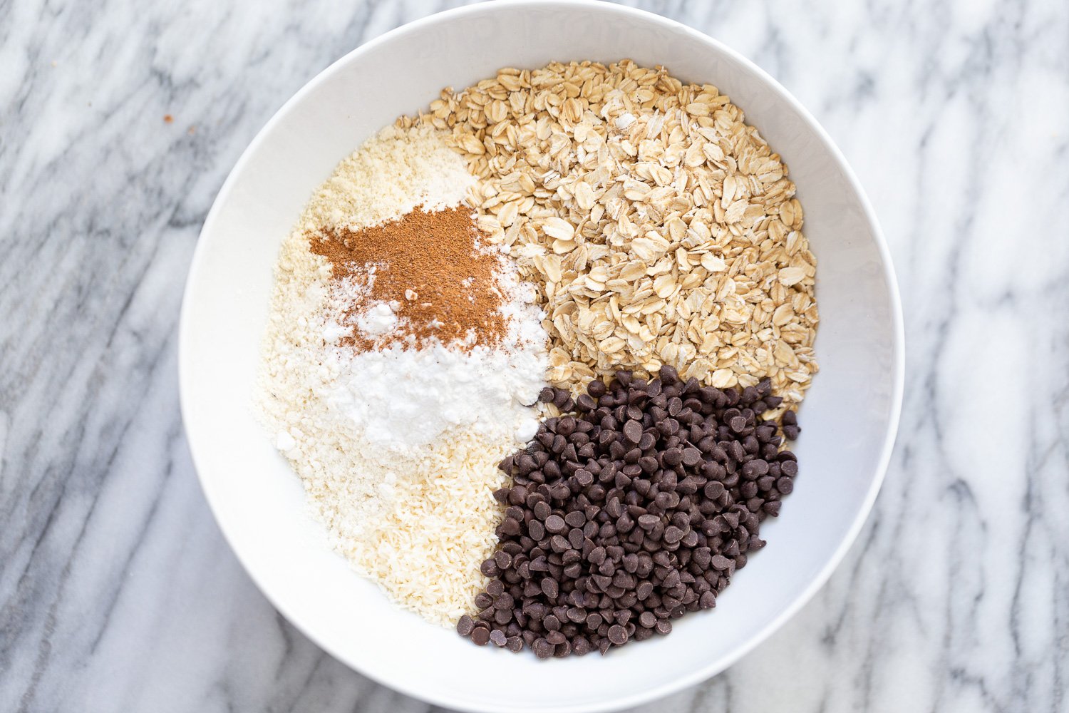 ingredients for making vegan chocolate chip waffles all gathered in a white bowl