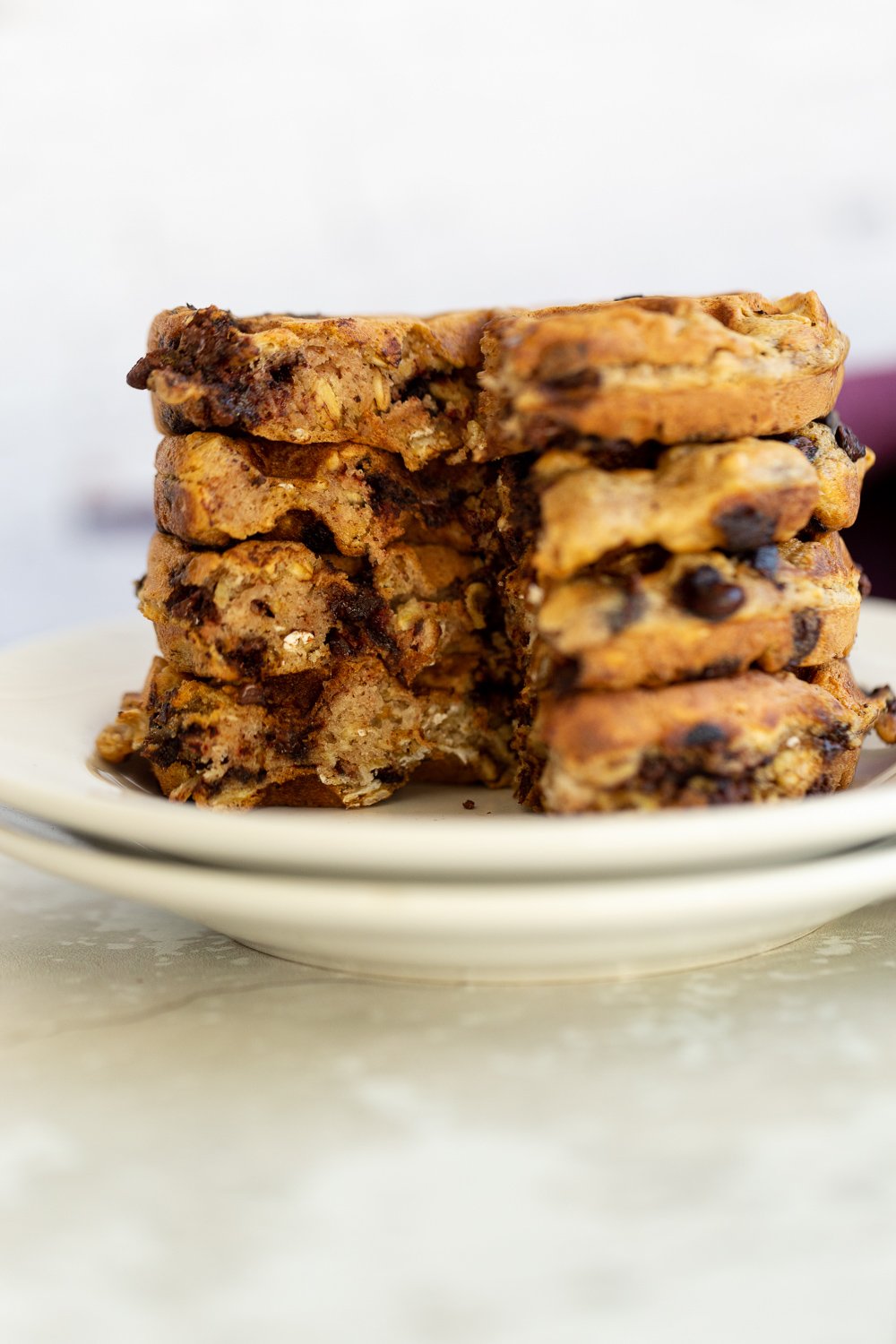 chocolate chip waffles side view of a stack of crispy vegan oatmeal chocolate chip waffles on a white plate