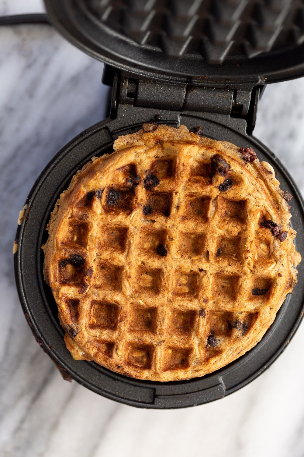 chocolate chip waffles a vegan oatmeal chocolate chip waffle being baked in a black iron waffle maker