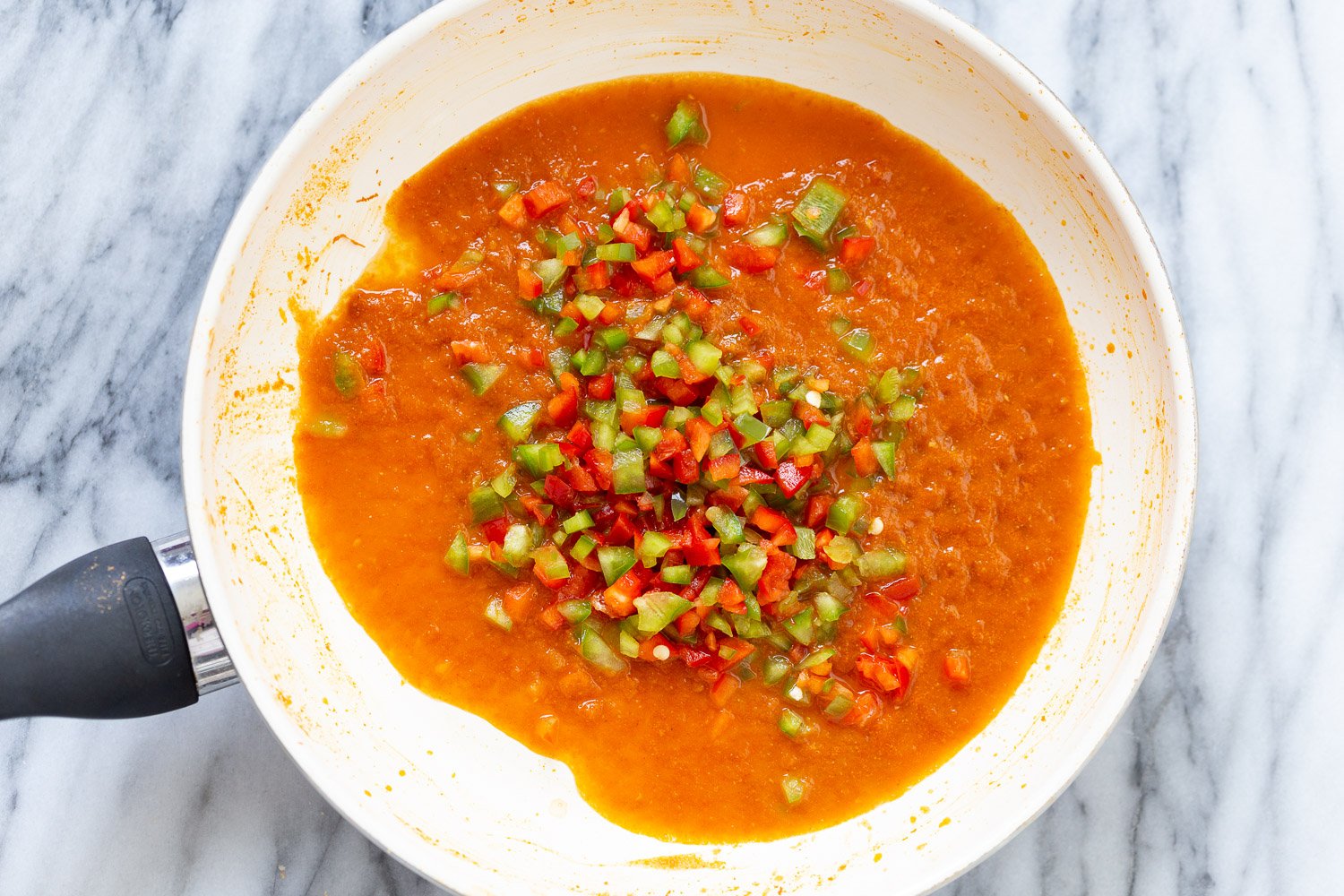 Spanish Cauliflower Rice overhead shot of a saucepan with tomato sauce and diced bell pepper for making Spanish cauliflower rice
