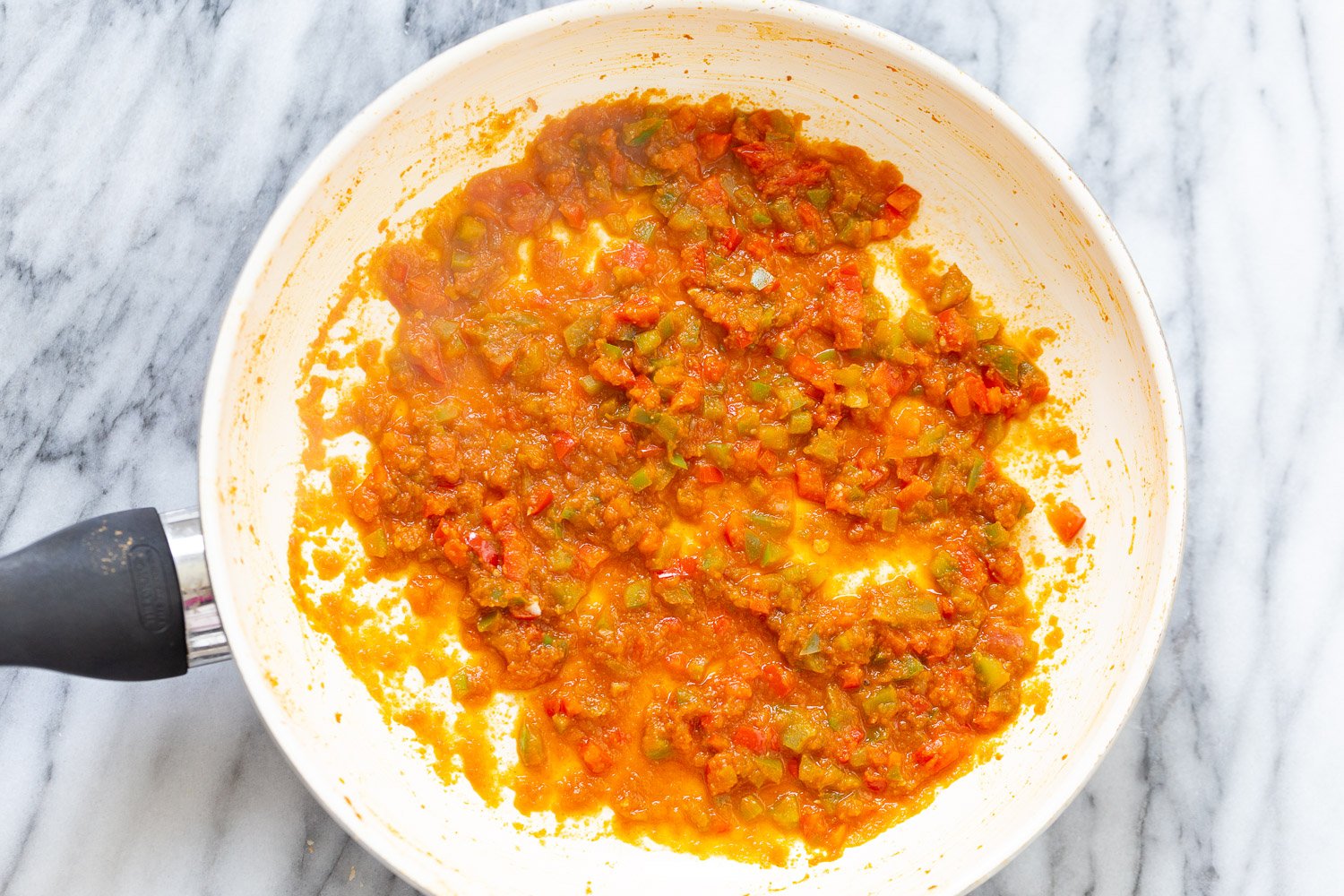 Spanish Cauliflower Rice overhead shot of reduced tomato and bell pepper sauce in a white sauce pan