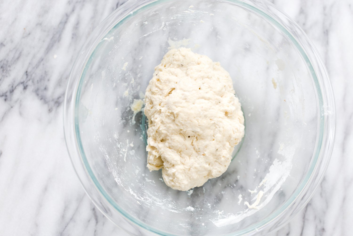 overhead shot of a glass bowl with vegan pizza dough