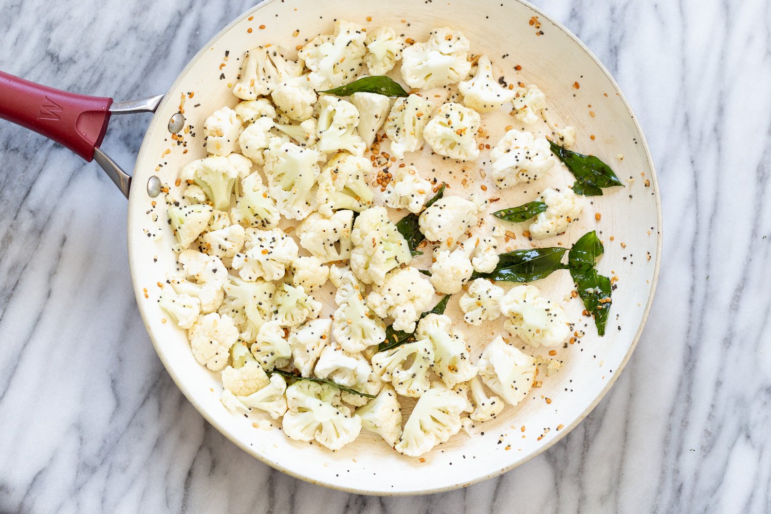 chickpea and spinach raw cauliflower florets being added to frying pan with Indian spices