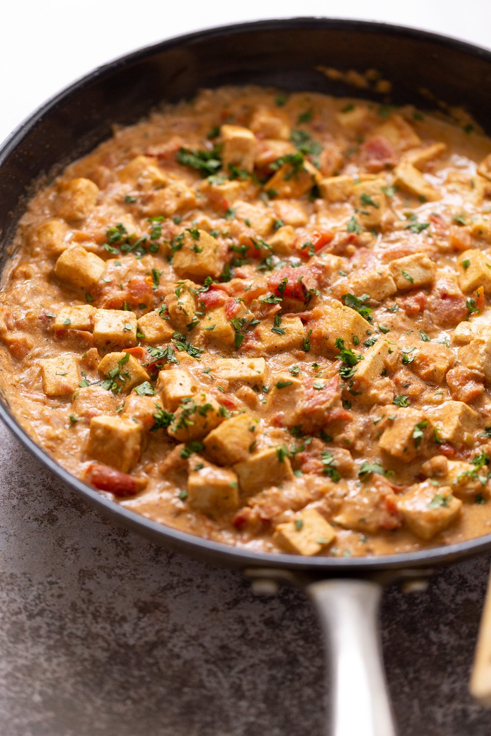 tofu in sauce side view of a skillet with Indian Vegan Tofu Dum Kali Mirch sprinkled with fennugreek
