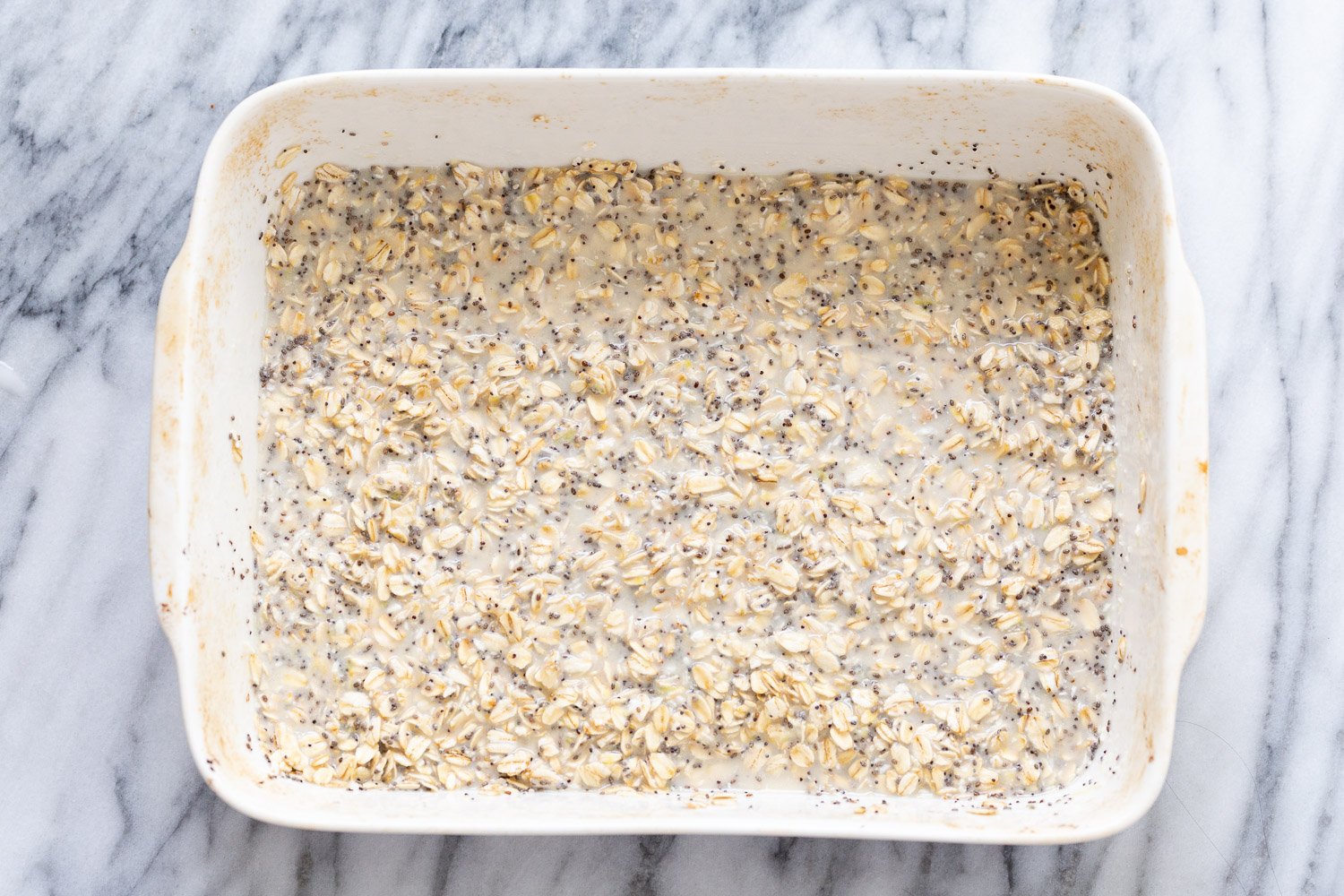 vegan baked oatmeal  rolled oats and chia seeds being mixed with plant based milk to make baked oatmeal