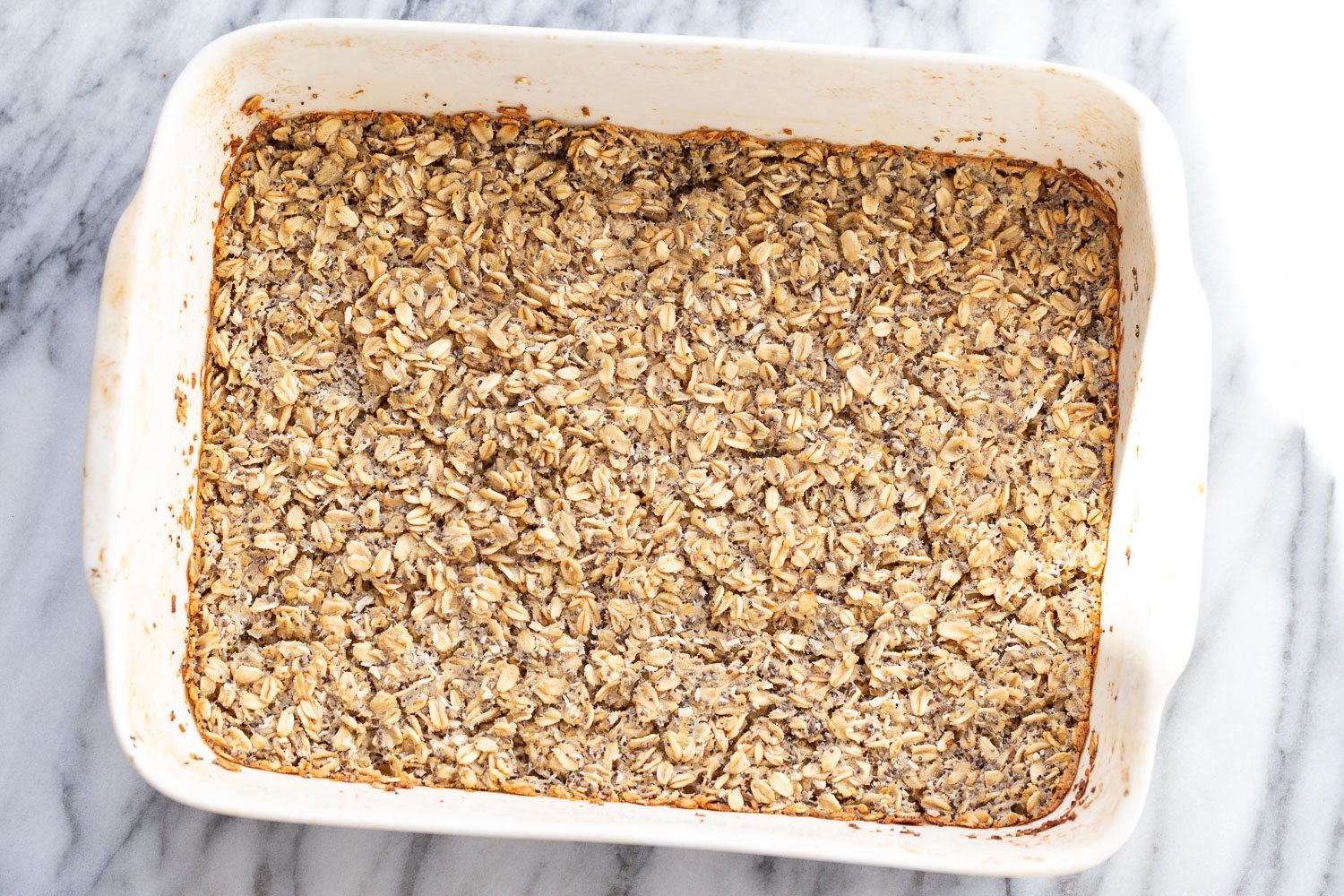 vegan baked oatmeal  overhead shot of freshly baked vegan baked poppyseed and lemon oatmeal in a white casserole dish