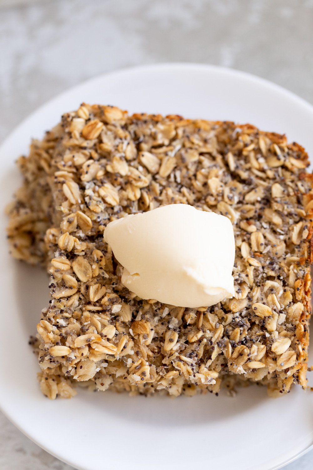 vegan baked oatmeal  overhead shot of a square of healthy vegan baked poppyseed lemon oatmeal topped with coconut whipped cream
