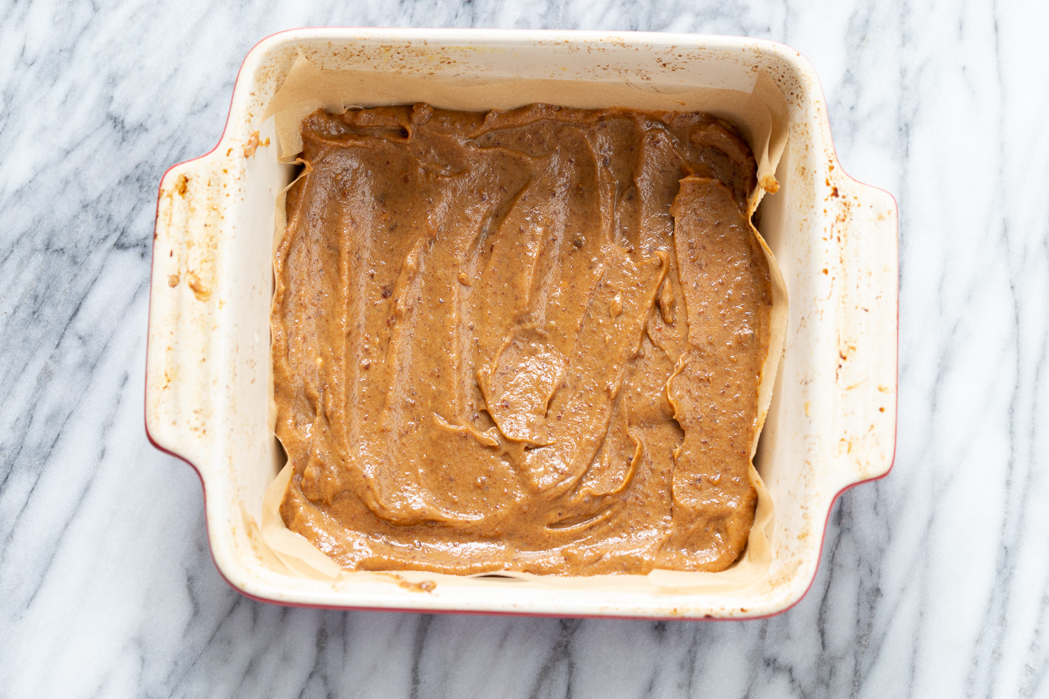 snickers recipe homemade vegan date caramel being spring onto cookie base to make vegan snickers snack bars recipe
