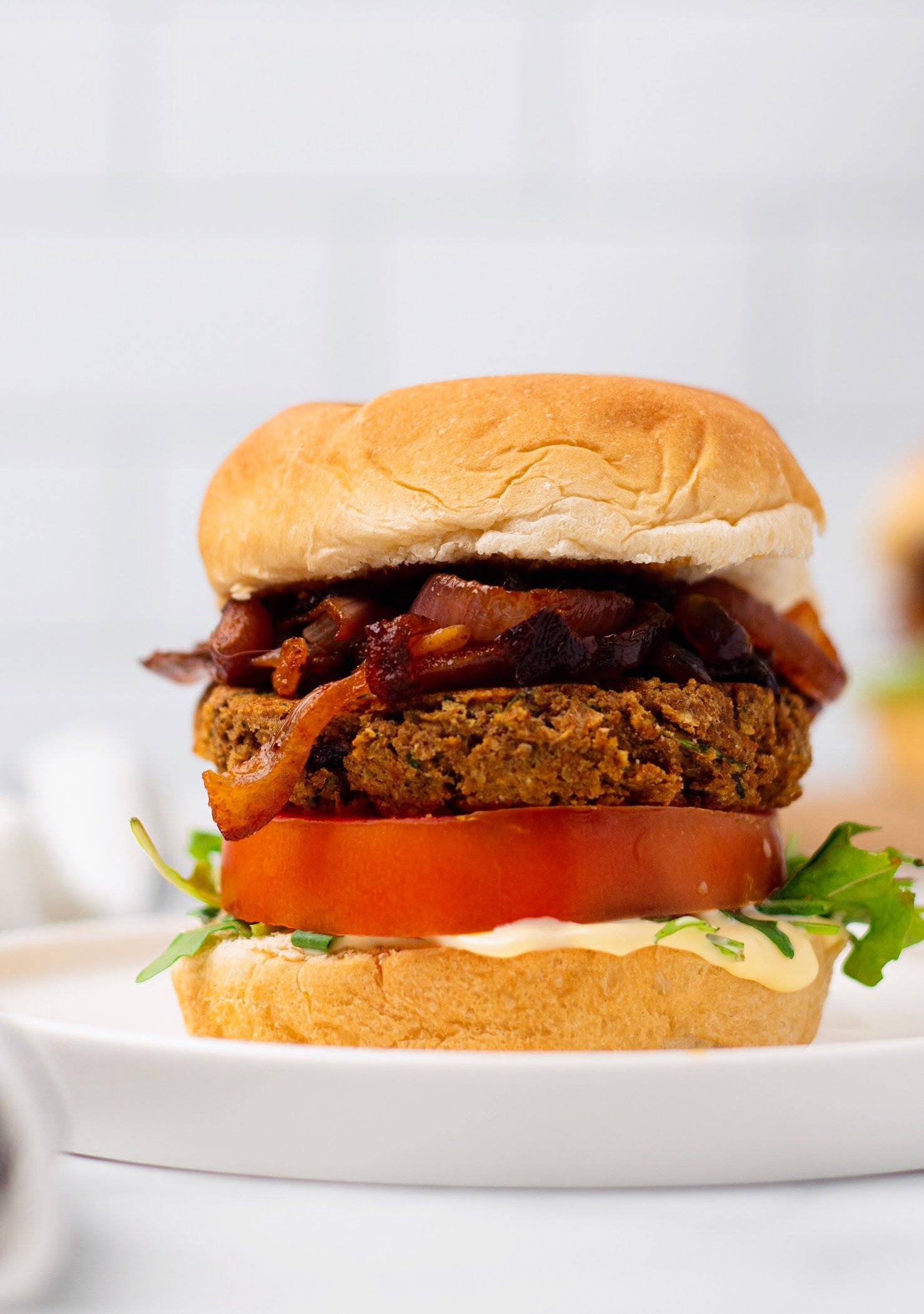 chickpea burger  side view of a vegan chickpea burger with caramelized onion, tomatoes, hummus and lettuce