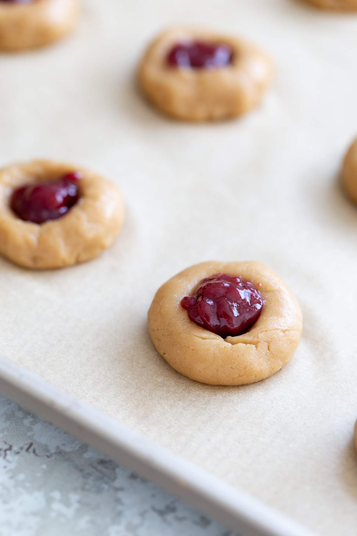 thumbprint cookies jam-filled pb&j vegan thumbprint cookies on a cookie sheet ready to be baked