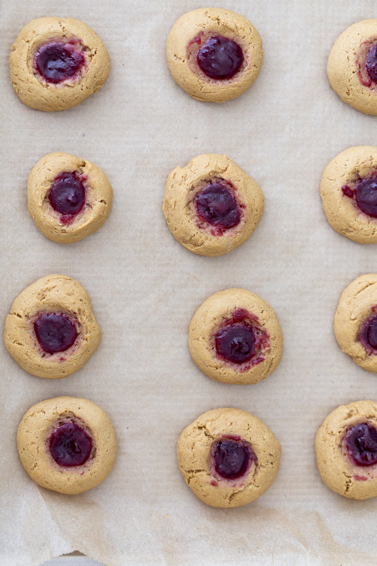 thumbprint cookies  overhead shot of a cookie tray with freshly baked pb&j thumbprint cookies
