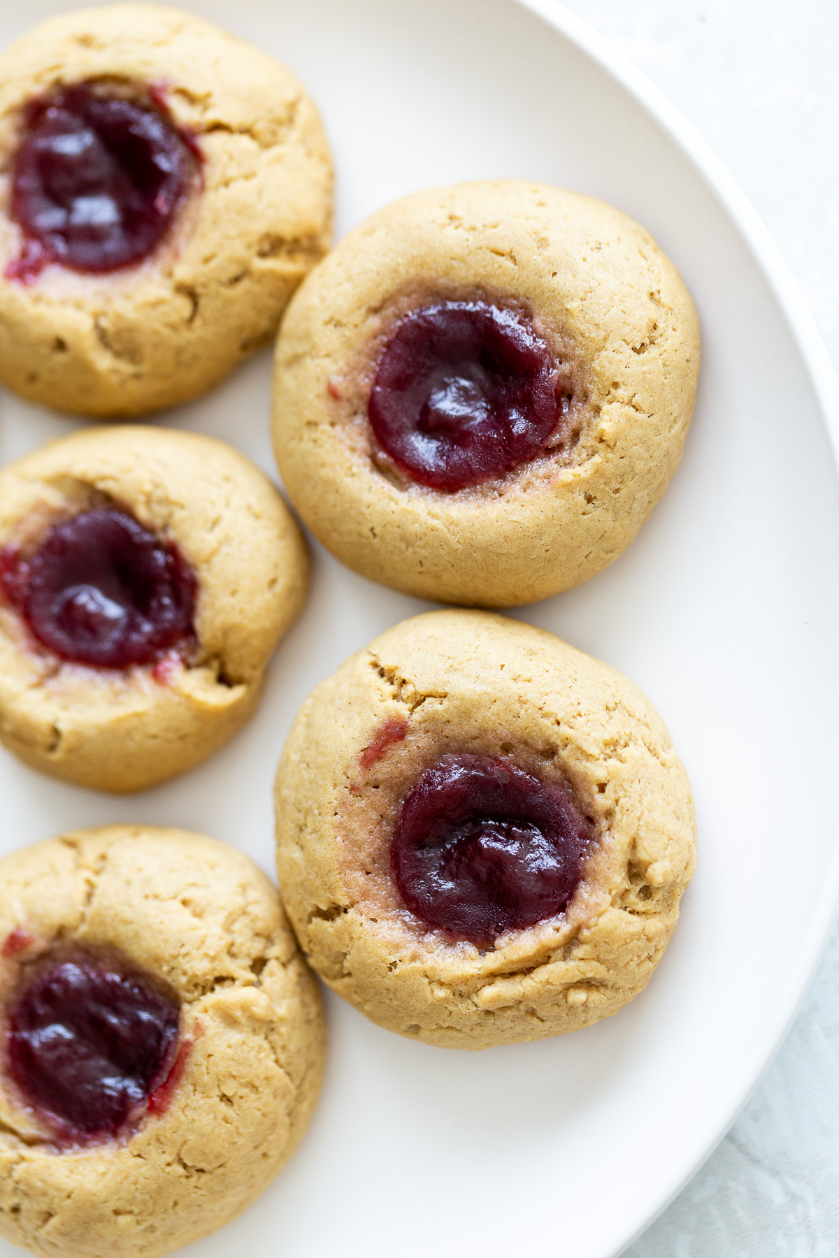 thumbprint cookies overhead shot of vegan pb & j thumbprint cookies on a white plate