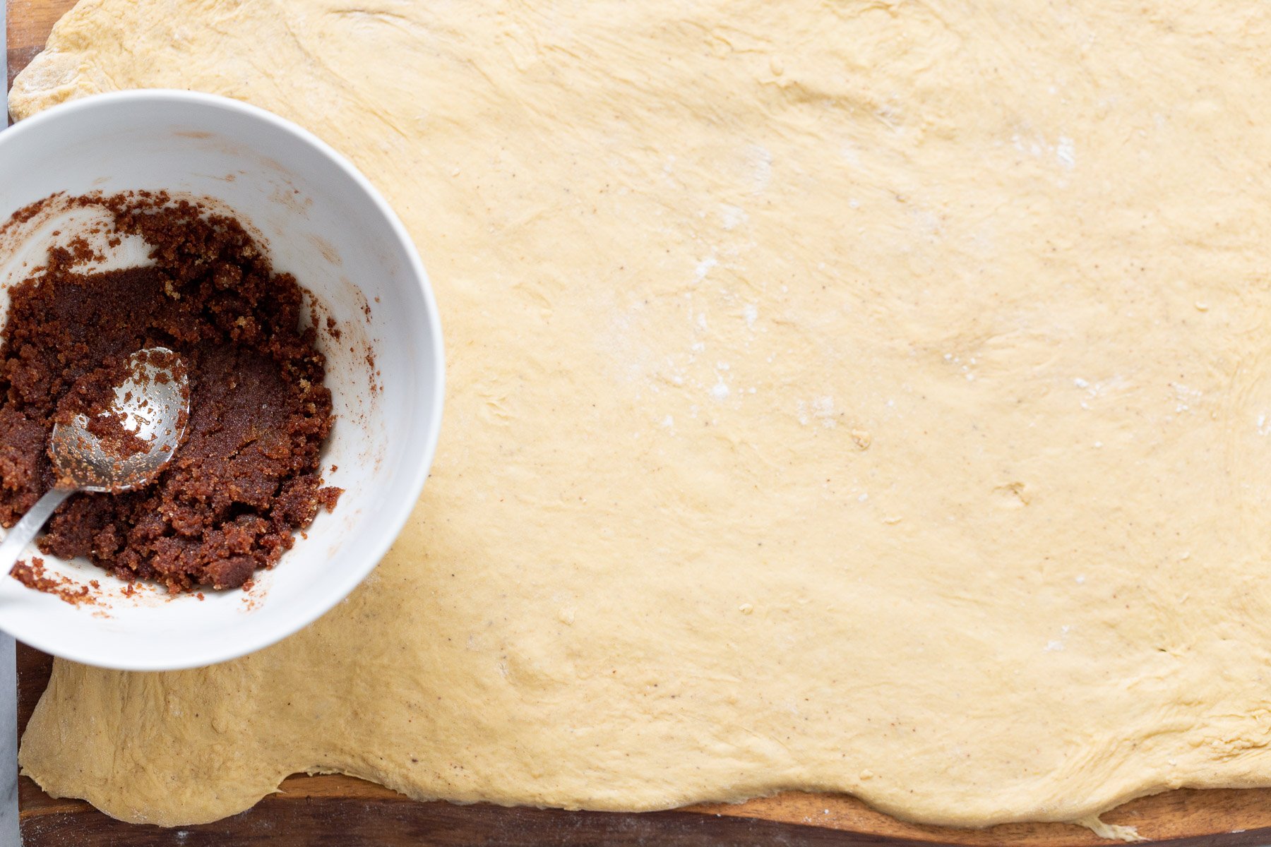 no yeast cinnamon rolls  brown sugar cinnamon mixture being spread on top of no yeast cinnamon roll dough