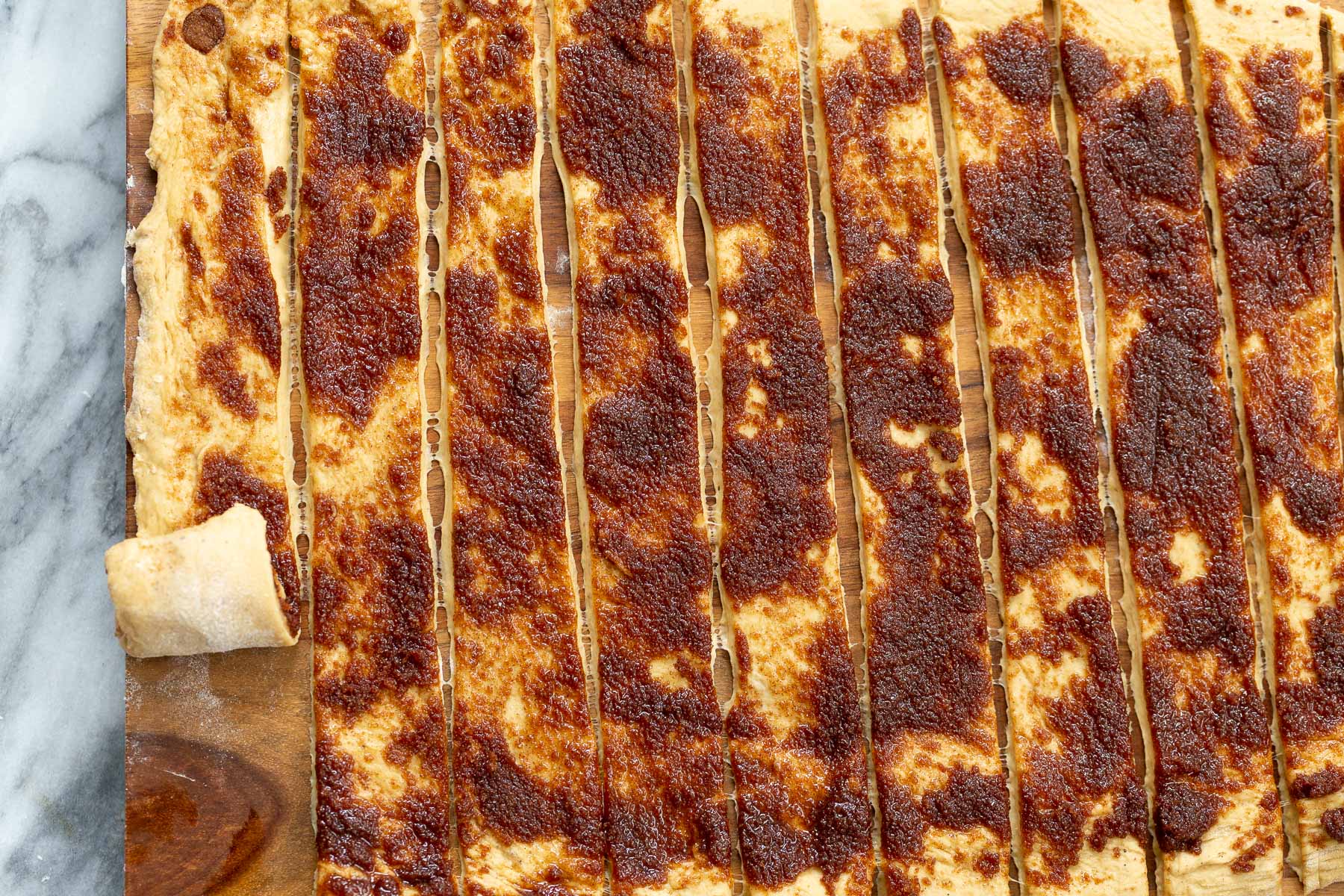 no yeast cinnamon rolls  rolled out cinnamon rolls dough being cut into strips and rolled up into buns