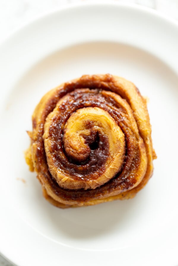 overhead shot of a vegan no yeast cinnamon roll with sweet potato on a white plate
