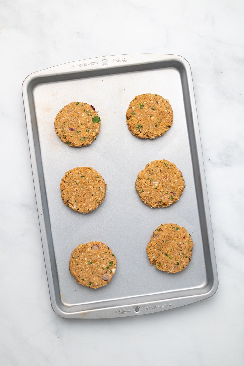 chickpea burger overhead shot of vegan chickpea burger patties lined up on a cookie sheet