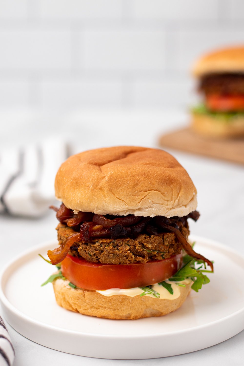 chickpea burger  side view of a Middle Eastern Za'atar spiced chickpea burger with caramelized onion and hummus on a white plate