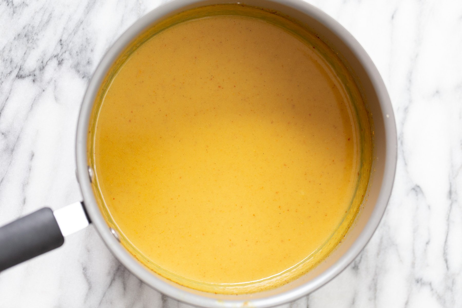 katsu curry tofu katsu curry sauce in a saucepan on a marble kitchen counter