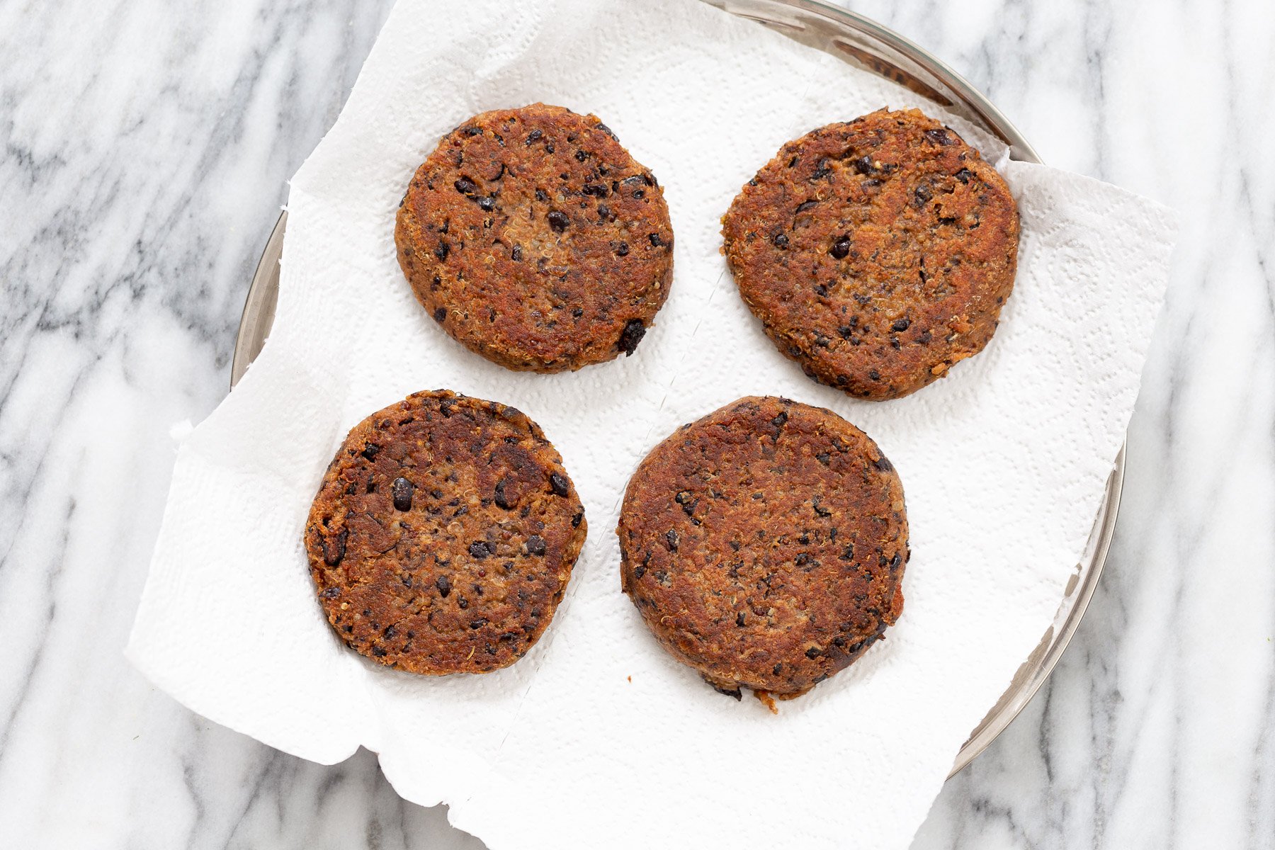 quinoa burger pan-fried black bean quinoa burger patties on a plate lined with paper towels