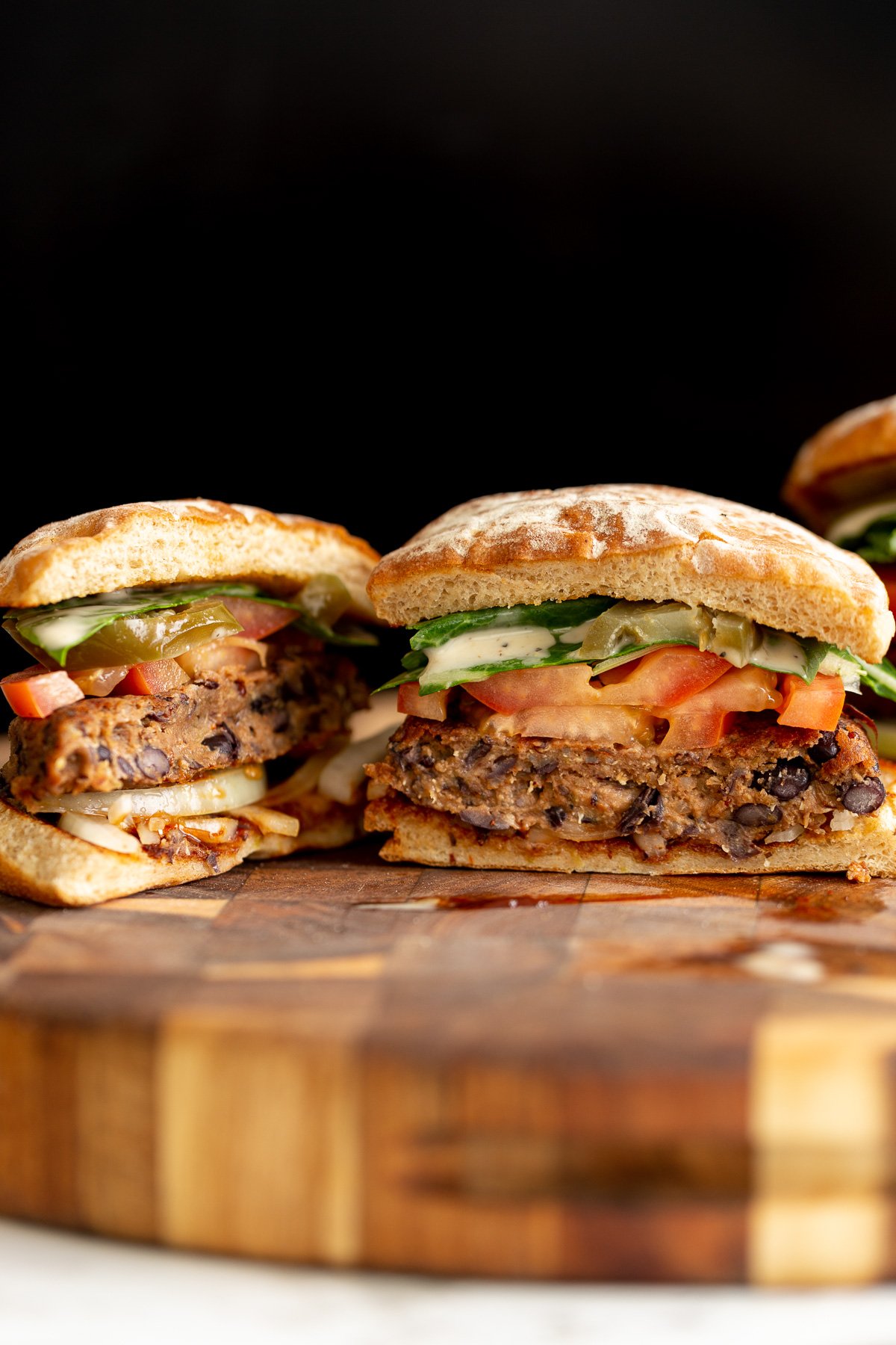 quinoa burger  a halved vegan black bean quinoa burger topped with tomato slices and drizzled with ranch sauce