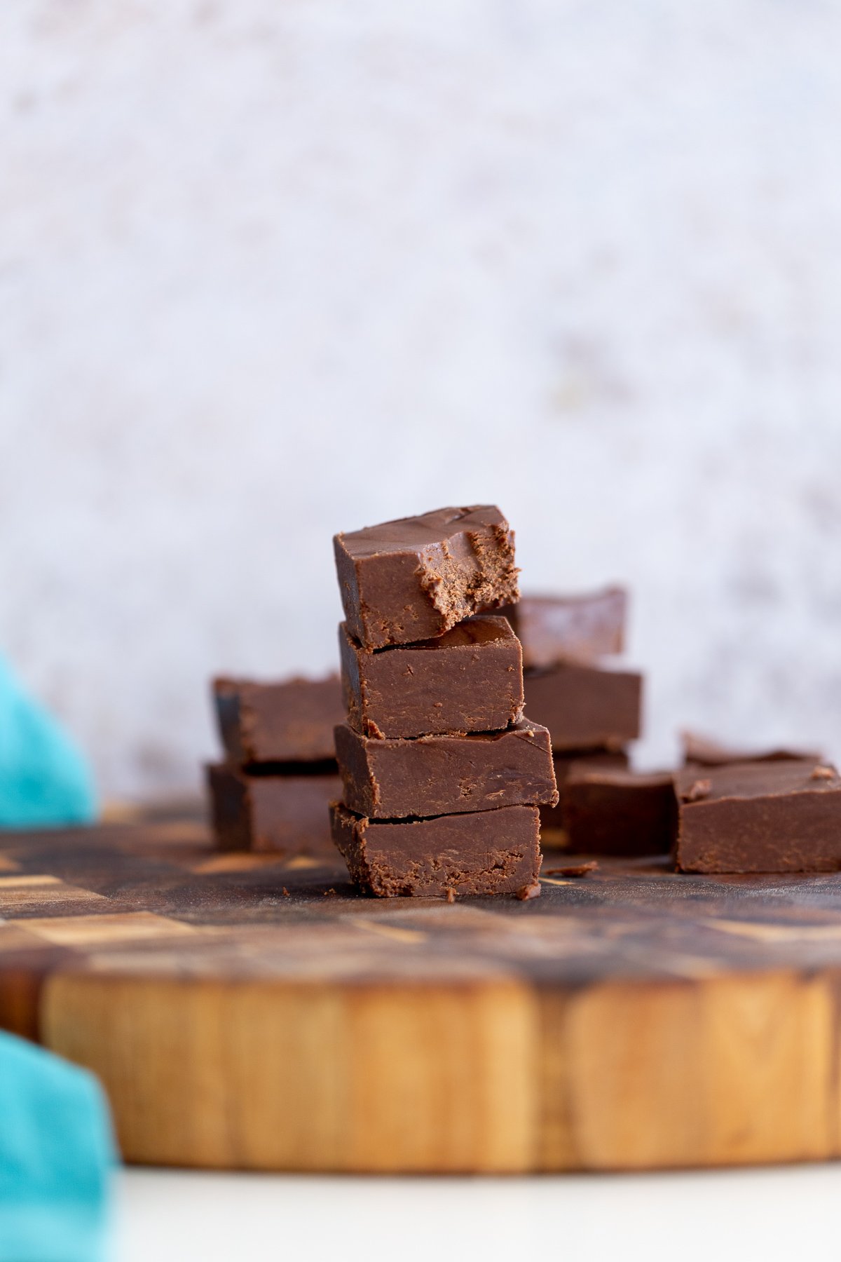 chocolate fudge recipe side view of a stach of vegan chocolate fudge on a wooden board