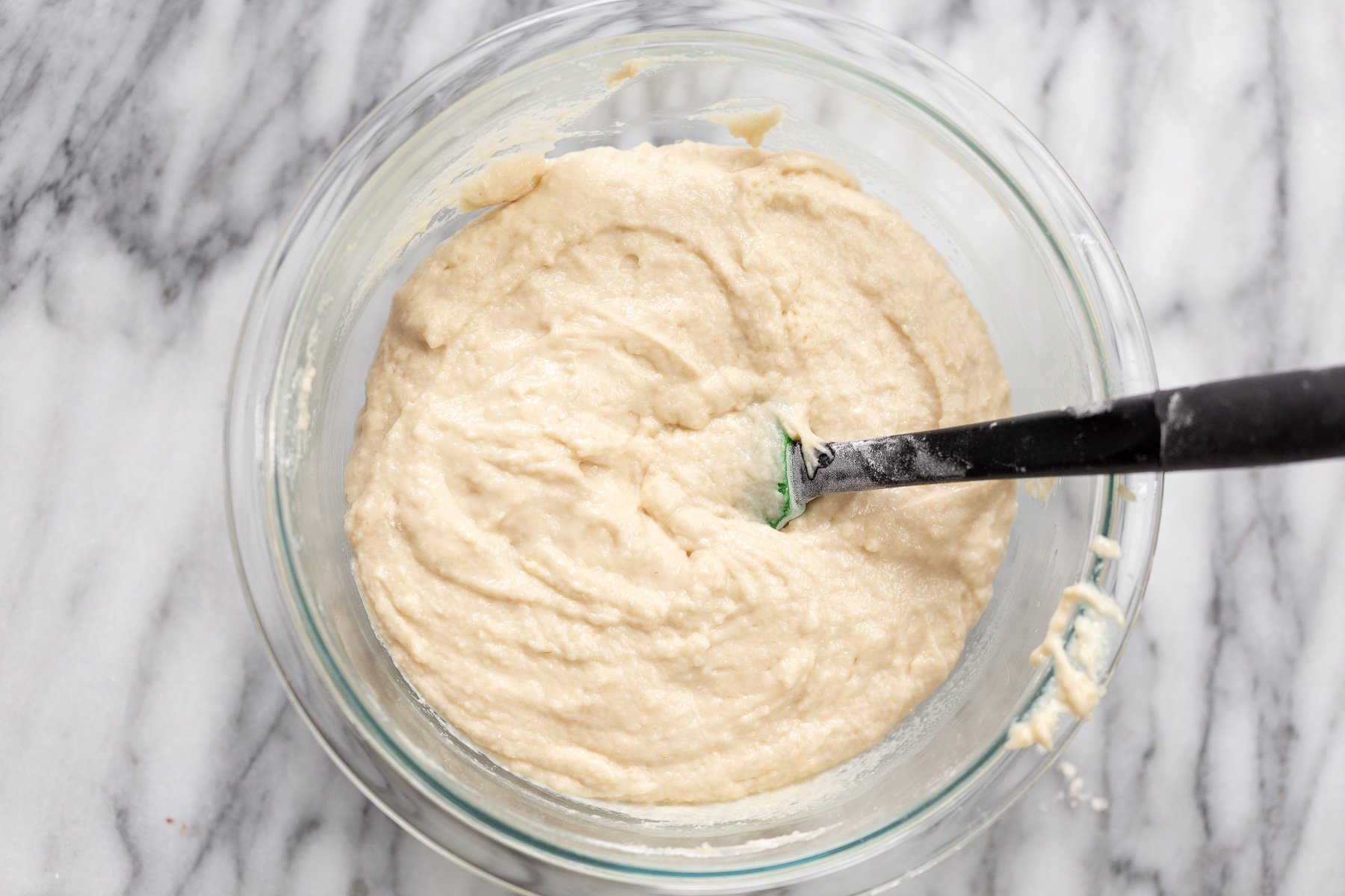 vegan white cake batter being mixed in a glass bowl 