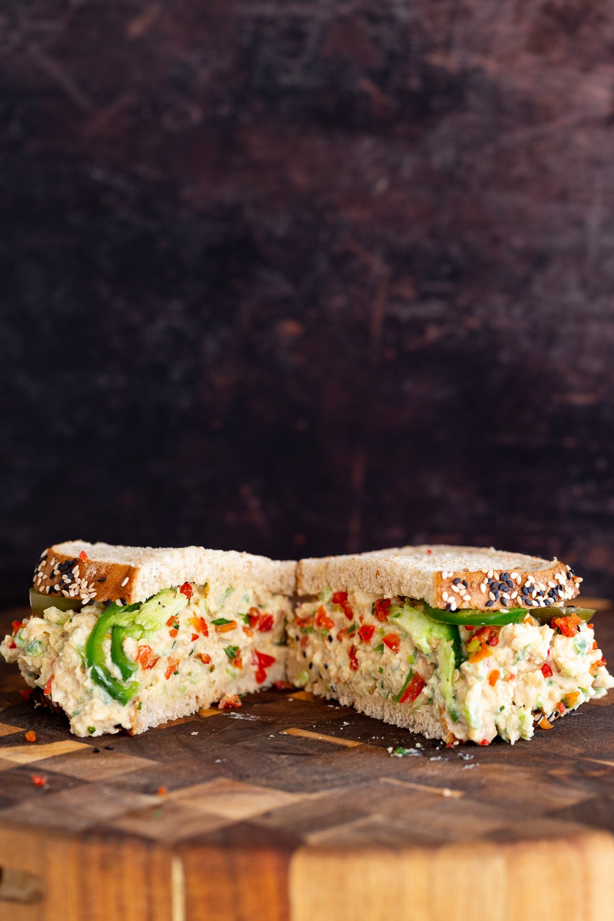 chickpea salad sandwich  halfed vegan jalapeño popper chickpea salad sandwich on a wooden chopping board