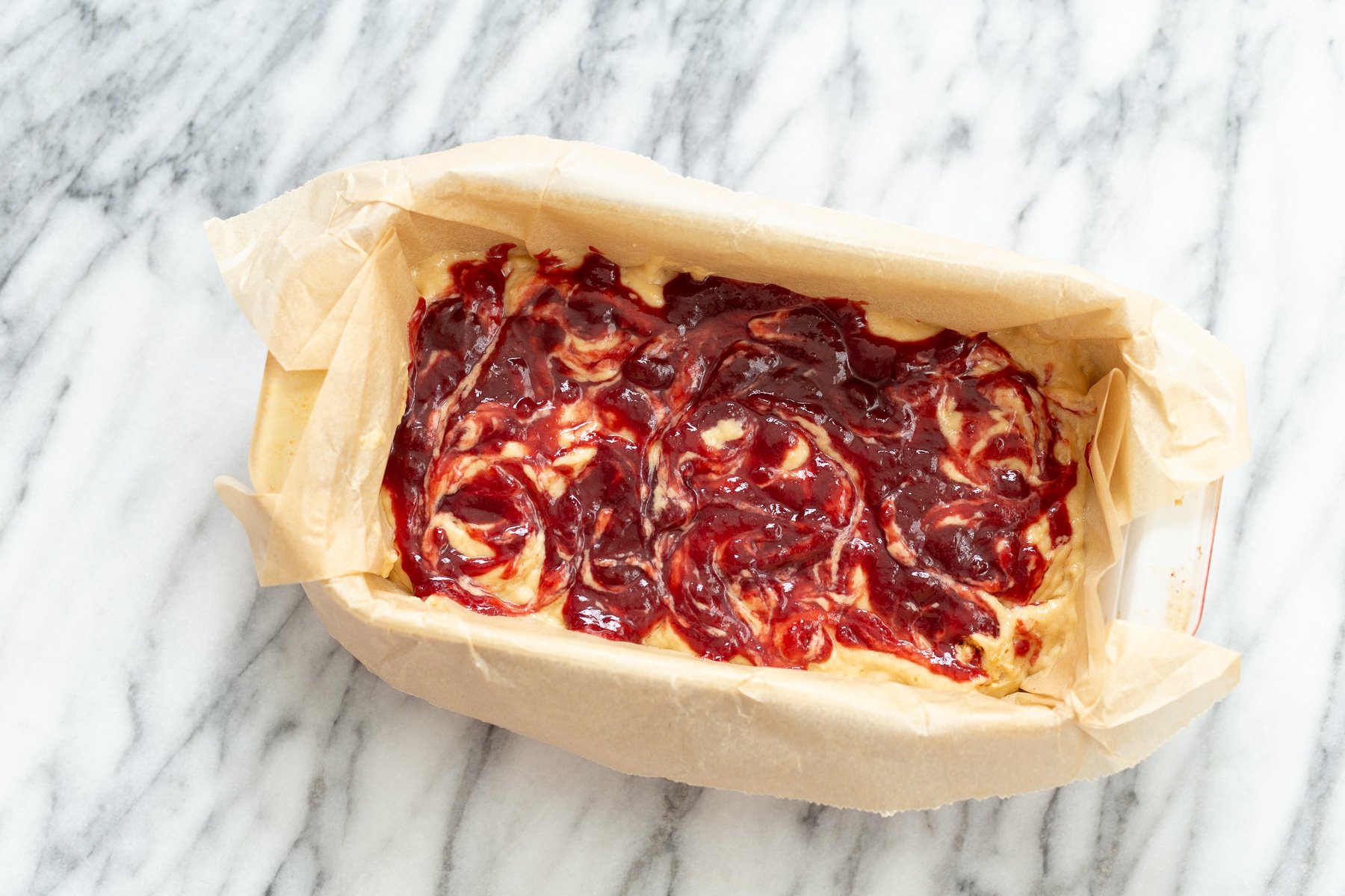 peanut butter and jelly cake  raspberry jam being swirled into peanut butter cake batter