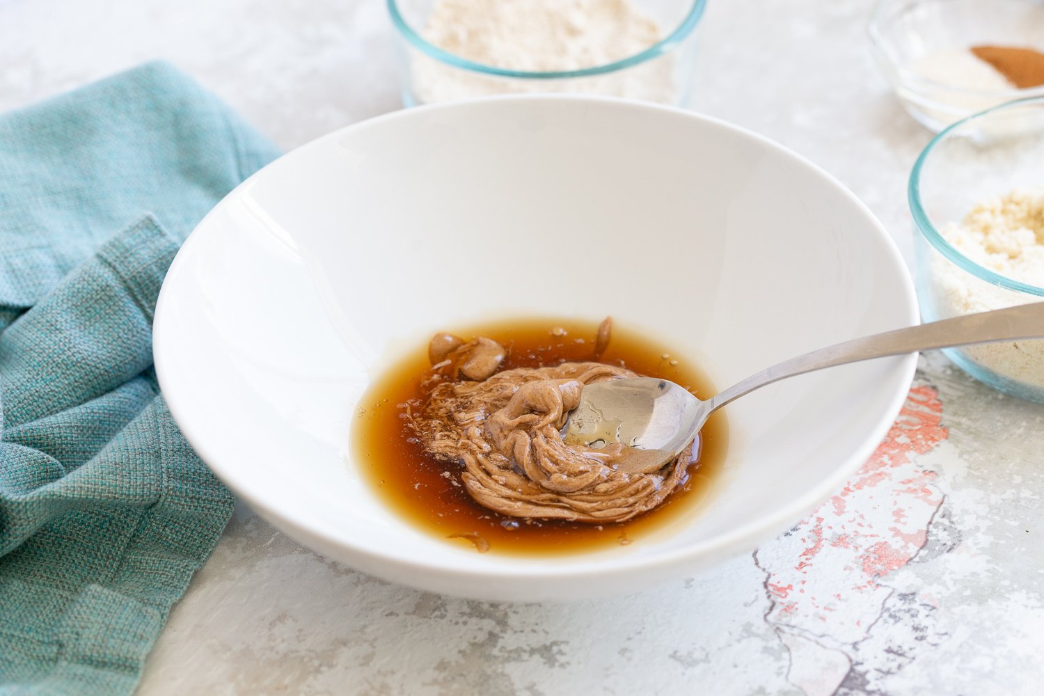 Snickerdoodle bites maple syrup and nut butter being stirred together in a small bowl