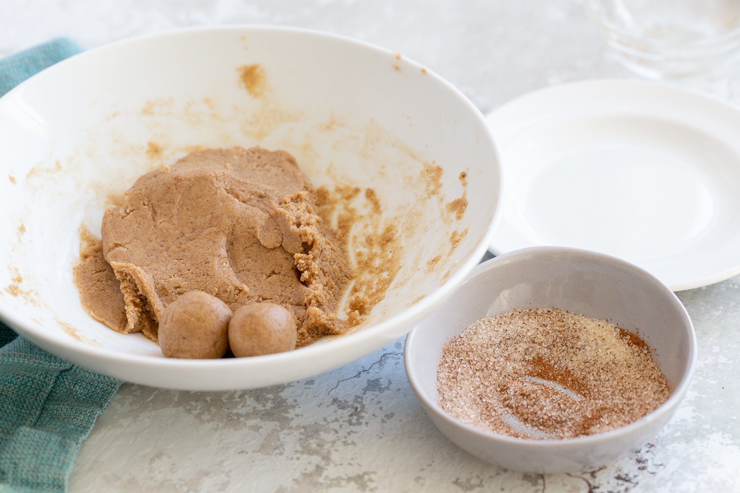 energy bites  snickerdoodle bites being rolled in a bowl with some cinnamon sugar for coating on the side