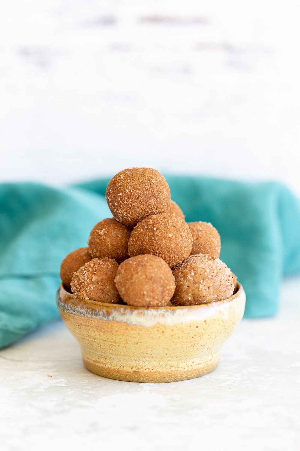 Snickerdoodle bites  a small bowl with healthy Vegan Snickerdoodle Bites with a blue kitchen towel